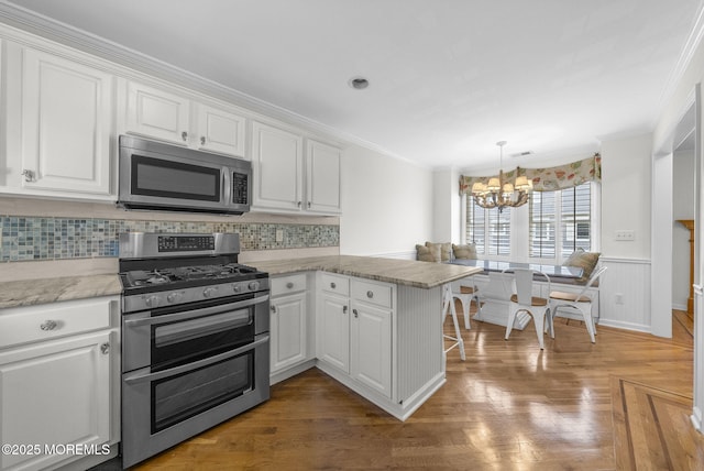 200 2nd Ave Unit 14, Belmar, NJ 07719 - kitchen featuring stainless steel appliances, a peninsula, ornamental molding, a chandelier, and white cabinetry