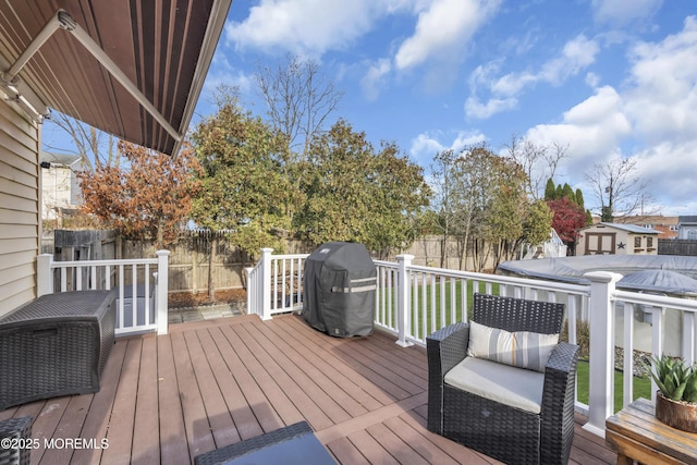 wooden deck with grilling area and a fenced backyard