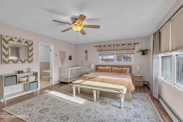 bedroom featuring baseboard heating, a ceiling fan, connected bathroom, and wood finished floors