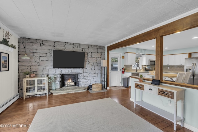 living area featuring dark wood-style flooring, a fireplace, and a baseboard radiator