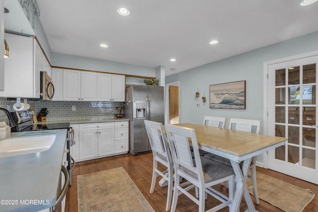 kitchen featuring tasteful backsplash, recessed lighting, appliances with stainless steel finishes, white cabinets, and light wood-type flooring