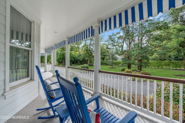 wooden deck featuring a porch and a lawn