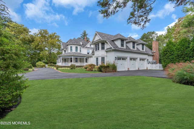 view of front of home with covered porch, driveway, and a front lawn