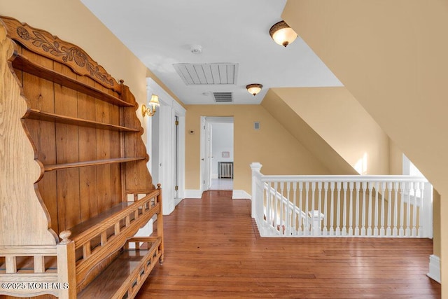 hall with radiator, visible vents, dark wood-style flooring, and an upstairs landing