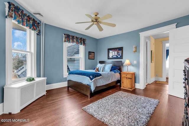 bedroom featuring baseboards, dark wood finished floors, visible vents, and radiator