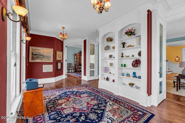 corridor featuring ornamental molding, wood finished floors, and an inviting chandelier