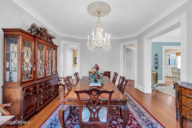 dining area featuring baseboards, crown molding, an inviting chandelier, and wood finished floors