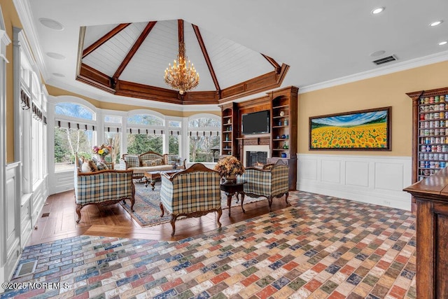 interior space featuring visible vents, a wainscoted wall, ornamental molding, a lit fireplace, and a chandelier