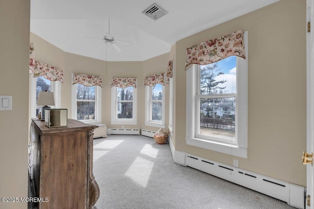 interior space with visible vents, a baseboard heating unit, a ceiling fan, and light colored carpet