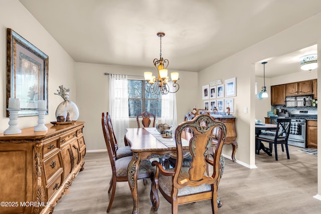 dining space with an inviting chandelier and light hardwood / wood-style flooring