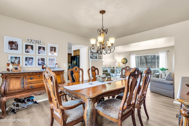 dining area with light wood-type flooring and a notable chandelier