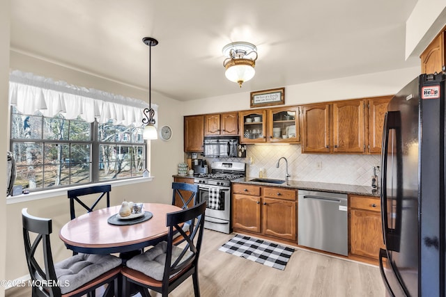 kitchen featuring decorative light fixtures, black appliances, light hardwood / wood-style floors, sink, and tasteful backsplash