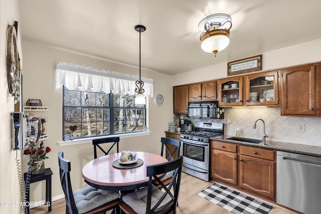 kitchen with sink, pendant lighting, dark stone counters, stainless steel appliances, and tasteful backsplash