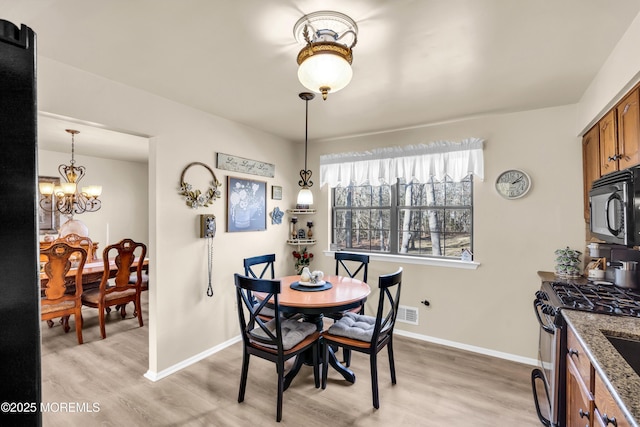 dining area with light hardwood / wood-style flooring and a chandelier