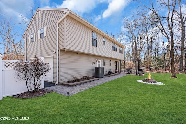 rear view of house featuring a garage, a fire pit, a lawn, and central air condition unit