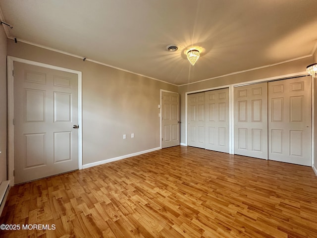 unfurnished bedroom with baseboards, light wood finished floors, two closets, and crown molding