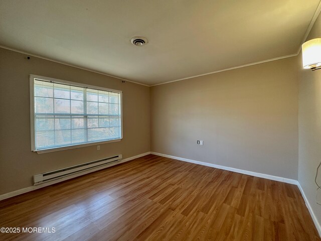 unfurnished room featuring baseboards, visible vents, ornamental molding, wood finished floors, and a baseboard heating unit