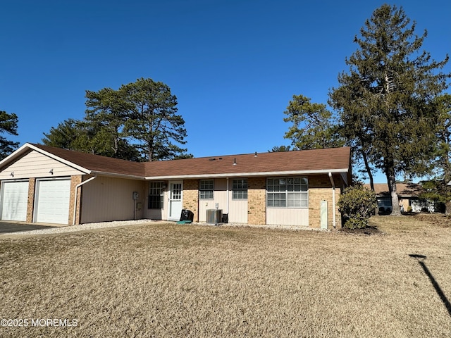 ranch-style house featuring brick siding, driveway, central AC, and an attached garage