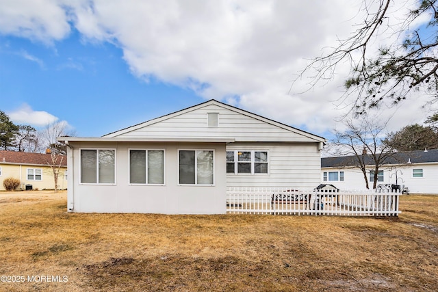 rear view of house with a lawn and fence