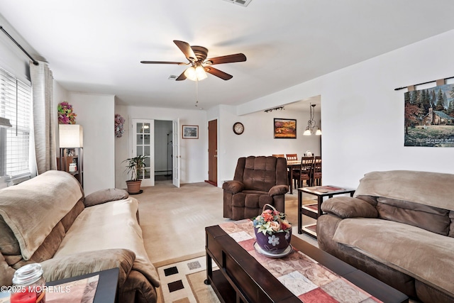 living area featuring a ceiling fan, light colored carpet, and visible vents