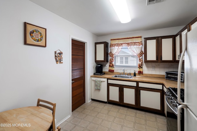 kitchen featuring white appliances, tasteful backsplash, light countertops, light floors, and a sink