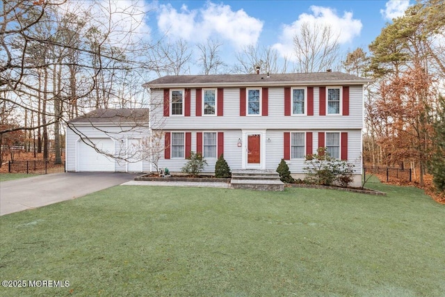 colonial-style house with an attached garage, fence, aphalt driveway, and a front yard