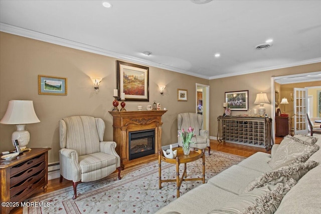 living area with baseboards, visible vents, a glass covered fireplace, crown molding, and light wood-type flooring