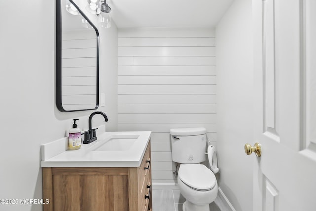 bathroom with vanity, toilet, and wooden walls