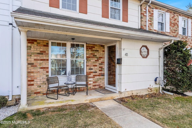 view of exterior entry featuring a porch and brick siding