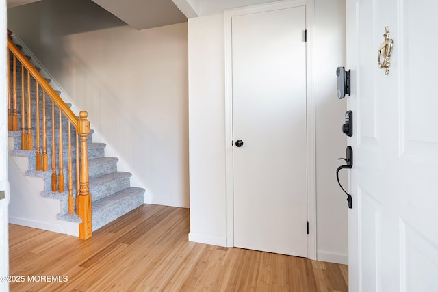 foyer featuring light wood-style floors, baseboards, and stairs