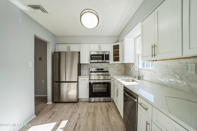 kitchen with visible vents, a sink, tasteful backsplash, white cabinetry, and appliances with stainless steel finishes