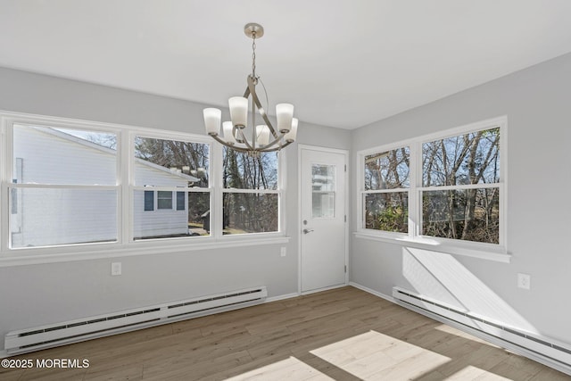 unfurnished dining area with a wealth of natural light, wood finished floors, baseboard heating, and a baseboard radiator