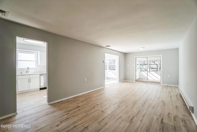 unfurnished room featuring a sink, visible vents, baseboards, and light wood finished floors