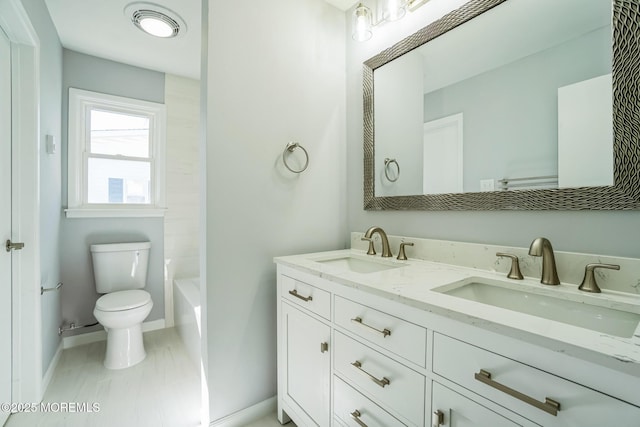 full bath with a sink, baseboards, toilet, and double vanity