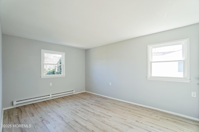 empty room featuring wood finished floors, baseboards, and a baseboard radiator