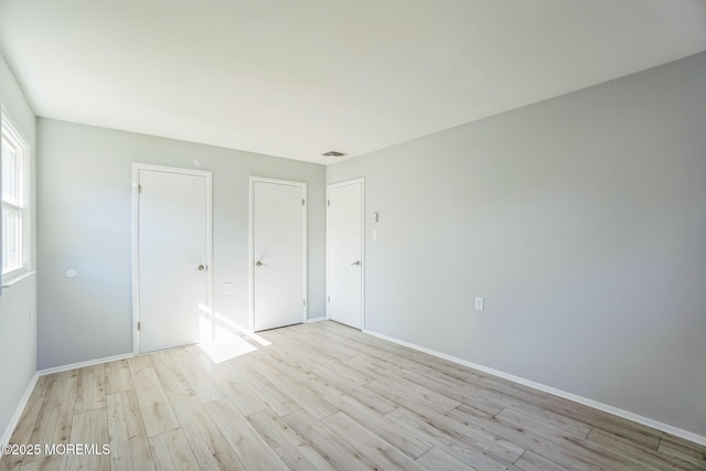 unfurnished bedroom with light wood finished floors, visible vents, and baseboards