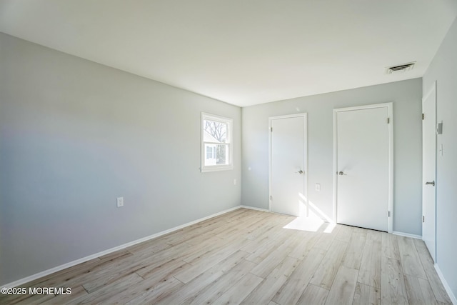 unfurnished bedroom with light wood-type flooring, visible vents, and baseboards