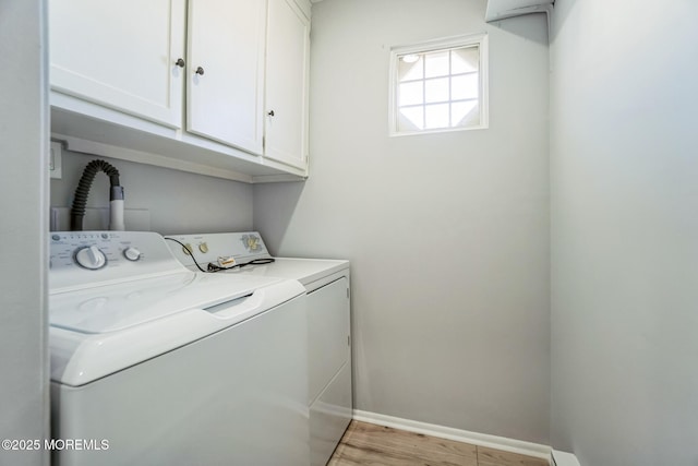 washroom with baseboards, cabinet space, washing machine and dryer, and light wood-style flooring