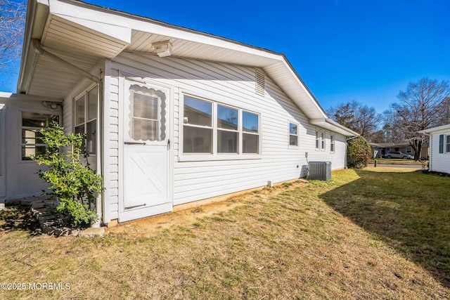 view of side of home with central AC unit and a lawn