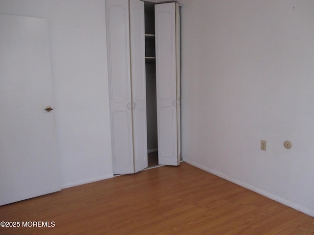 unfurnished bedroom with wood-type flooring and a closet