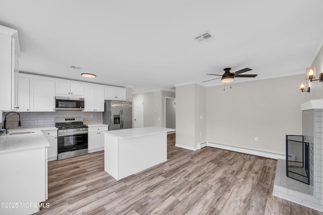 kitchen with a center island, light countertops, appliances with stainless steel finishes, white cabinetry, and a sink