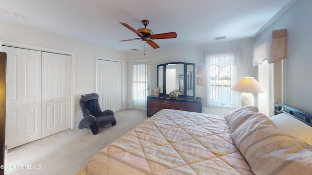 carpeted bedroom featuring ceiling fan and two closets