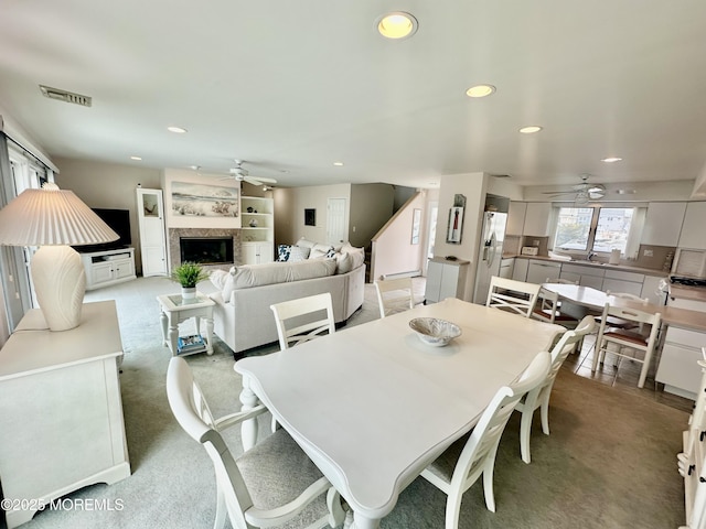 dining area featuring light carpet, a high end fireplace, and ceiling fan