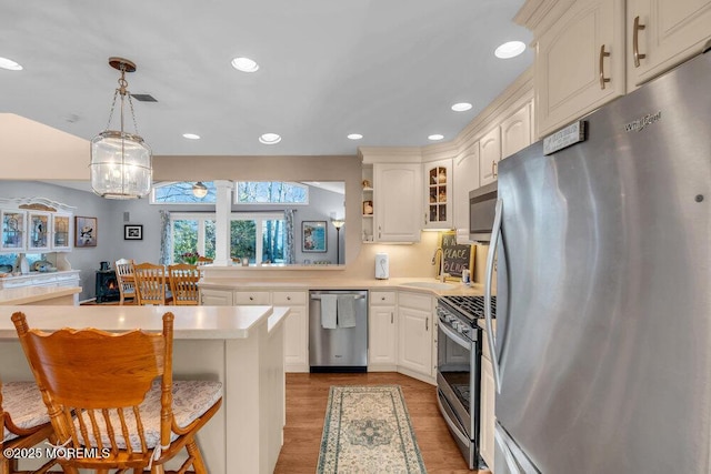 kitchen with decorative light fixtures, stainless steel appliances, dark hardwood / wood-style flooring, a kitchen breakfast bar, and sink