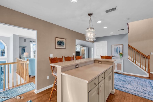 kitchen with decorative light fixtures, an inviting chandelier, light hardwood / wood-style floors, white cabinets, and a breakfast bar