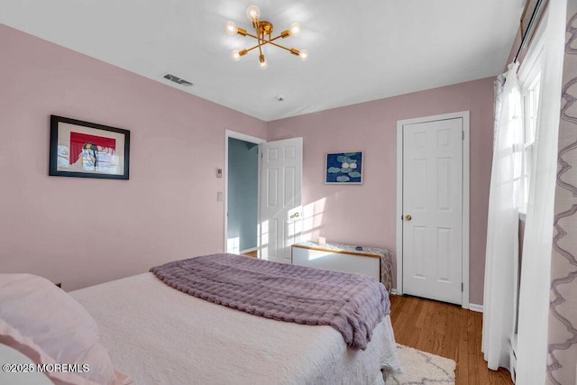 bedroom with light hardwood / wood-style flooring, a chandelier, and vaulted ceiling