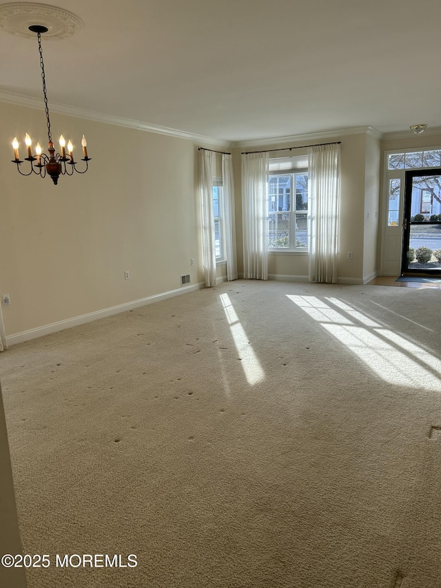 spare room with baseboards, carpet floors, ornamental molding, and an inviting chandelier