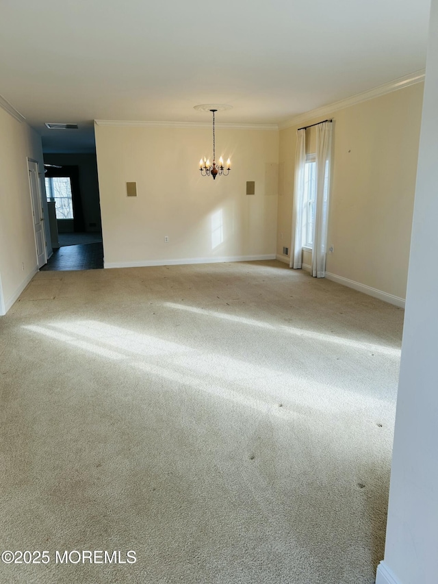 carpeted spare room with ornamental molding, visible vents, baseboards, and an inviting chandelier