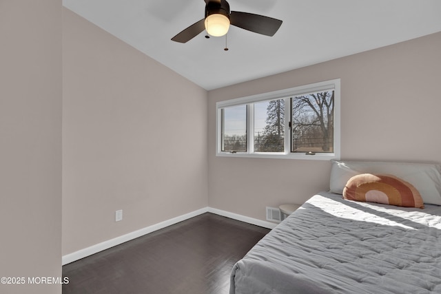 bedroom with dark wood-style flooring, lofted ceiling, visible vents, a ceiling fan, and baseboards