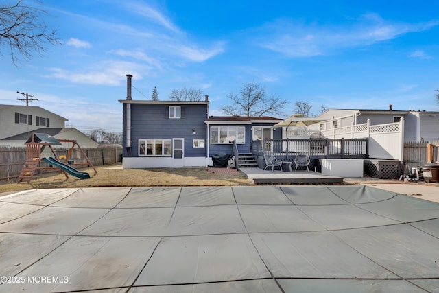 back of house with a deck, a playground, fence, and a residential view